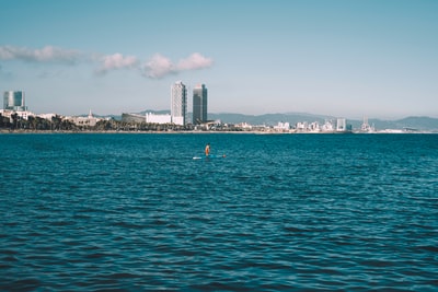 白天人游泳在大海附近的城市建筑
